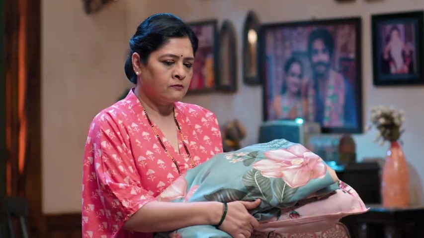 Renuka holding a pillow, looking upset, as she decides to sleep on the couch