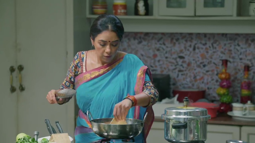 Anupama cooking in the rich family’s kitchen, looking focused