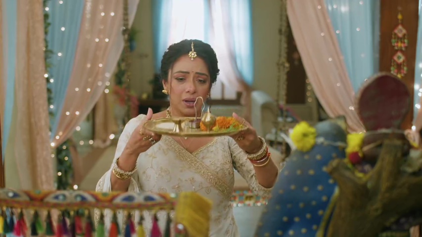 Anupama praying with a worried look as the lamp flickers