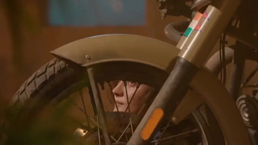 Isha hiding behind bike, looking scared as guards search for her