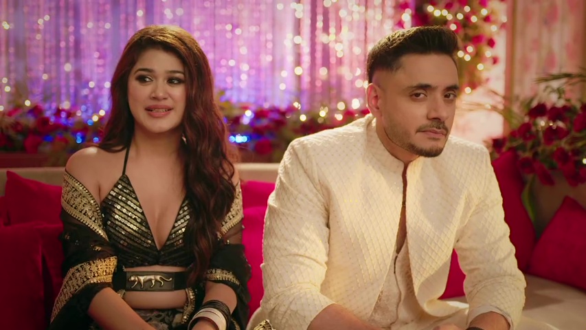 Mallika and Vikrant on stage, smiling for guests, while Aishwarya looks tense in the background