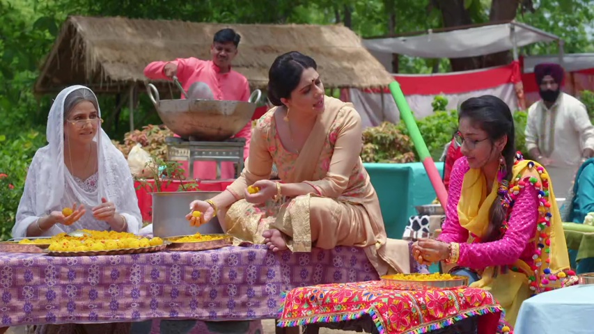 Preeth with her family, smiling while making laddoos for the wedding