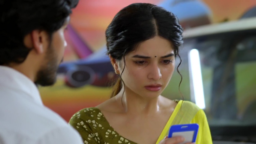 Savi looking anxious at the airport, holding her phone, waiting for Ridhi